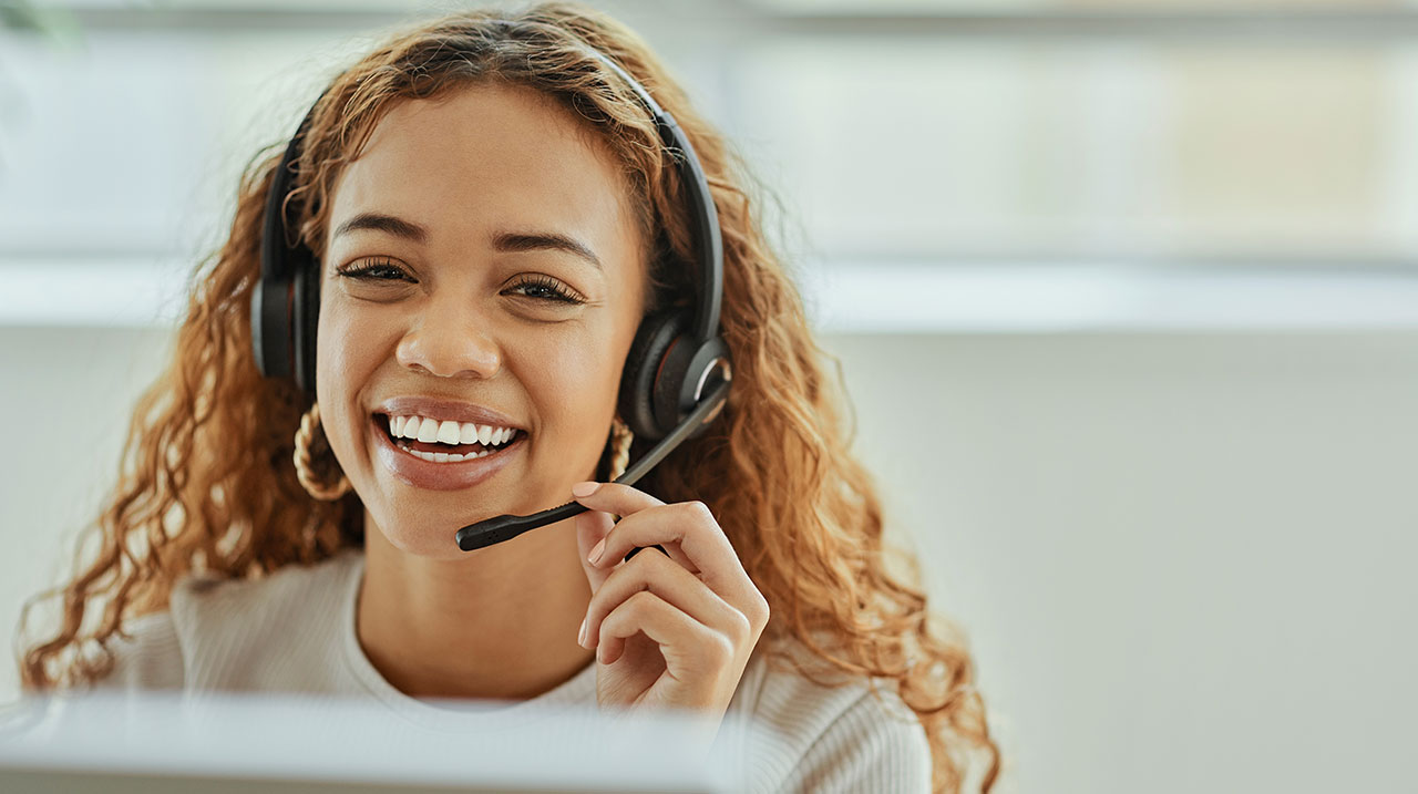 Giovane operatrice sorridente del servizio clienti con cuffie e microfono.