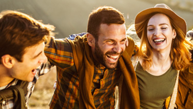 Gruppo di giovani amici sorridenti camminano su in collina in una giornata autunnale.