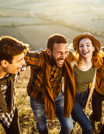 Gruppo di giovani amici sorridenti camminano su in collina in una giornata autunnale.