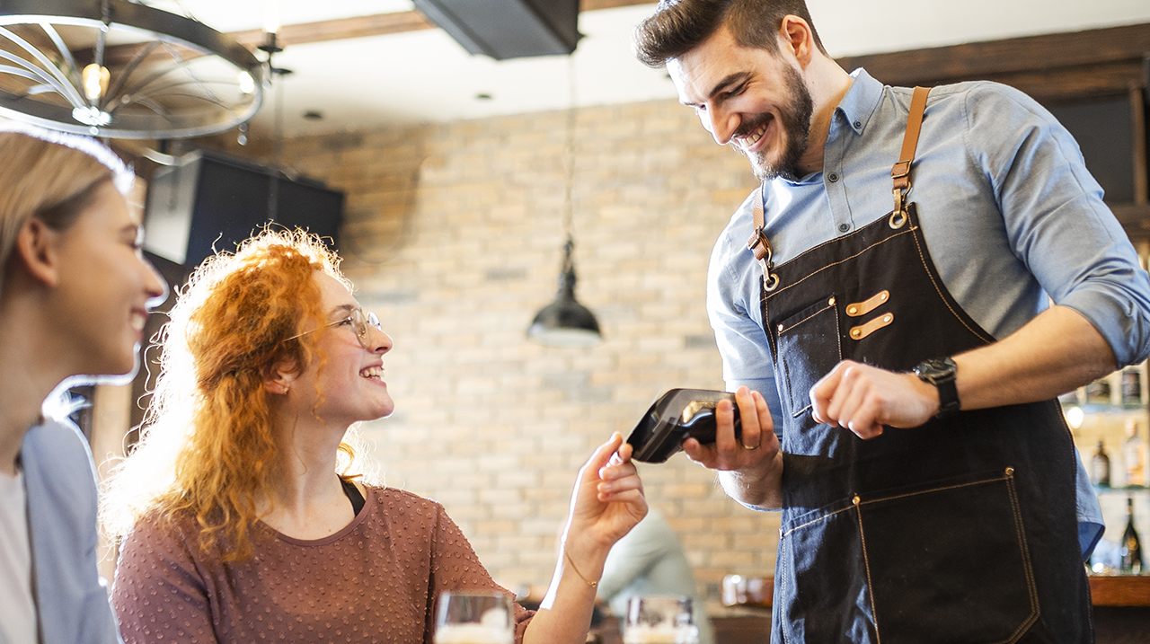 Coppia di amiche paga con la carta contactless in un ristorante