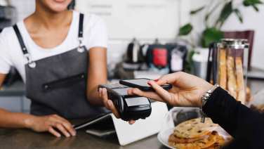 Giovane donna paga in un caffè con il proprio smartphone