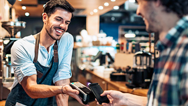 Un ragazzo paga con lo smartphone in un caffè.