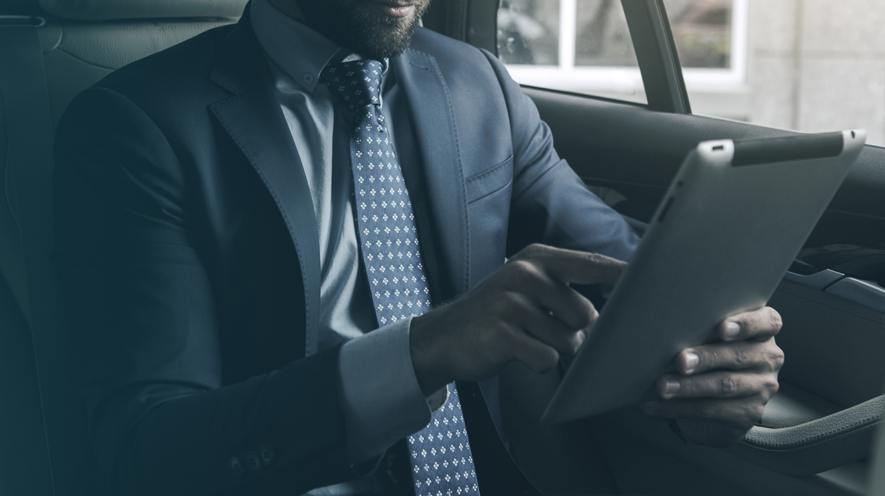 Uomo in abito elegante opera in mobilità tramite il suo tablet