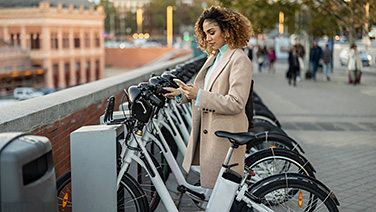 Donna che noleggia una bicicletta elettrica tramite smartphone al parcheggio