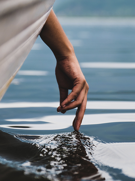 Una mano sfiora l'acqua.