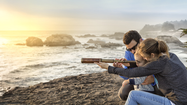 .Famiglia con cannocchiale guarda verso l'oceano.